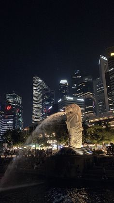 the city skyline is lit up at night with water spewing from it's fountains