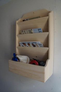 there is a wooden shelf with magazines and other items in it that are attached to the wall