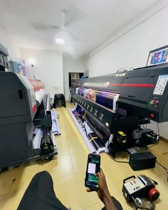 a person is using a cell phone to take a photo of a large print machine