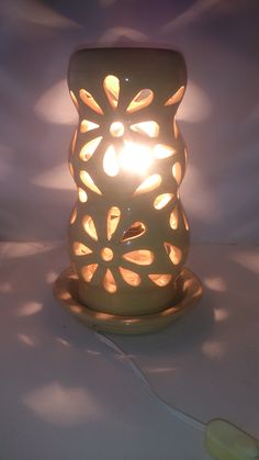 a lit candle sitting on top of a table next to a light bulb in the shape of a flower
