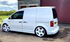 a white van is parked in front of a building with a red garage door behind it