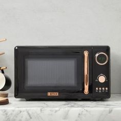a black microwave oven sitting on top of a counter next to other kitchen utensils