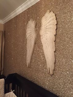 two angel wings are hanging on the wall next to a baby's crib