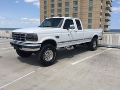 a white pick up truck parked in a parking lot next to a large brown building