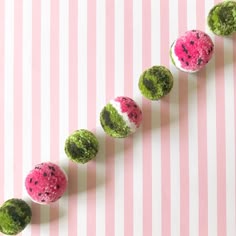 a pink and white striped wall with some green and pink balls on top of it