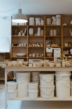 many white buckets are stacked on a shelf in a room with shelving and shelves