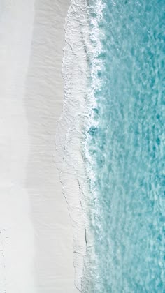 an aerial view of the ocean and beach with people walking on the sand near it