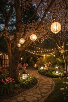 an outdoor walkway with lanterns and flowers on the sides at night time, lit by lights strung from trees