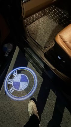 someone standing in front of a bmw logo on the floor next to their car door