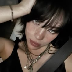 a close up of a person wearing a black shirt and some necklaces on her neck