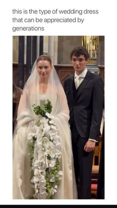 a man and woman standing next to each other in front of a wedding dress with flowers on it