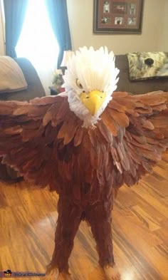 an eagle made out of paper mache on a wooden floor in a living room