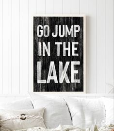 a black and white poster with the words go jump in the bay hanging above a couch