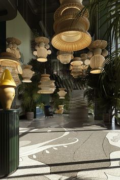 a room filled with lots of hanging lights and plant pots on the floor next to each other