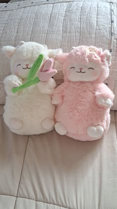 two stuffed animals sitting on top of a bed next to each other in front of a pillow