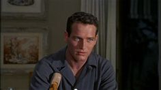 a man sitting at a table in front of a microphone and looking off into the distance