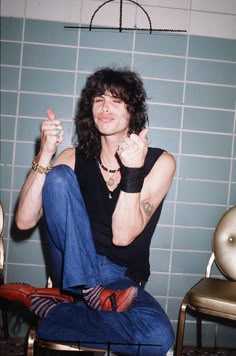 a man sitting on top of a chair in front of a blue tiled bathroom wall