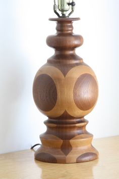 a wooden table lamp sitting on top of a wooden table next to a white wall