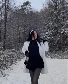 a woman is walking in the snow with her hand on her hip and wearing tights