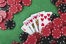 playing cards and poker chips on a green felt table with red black and white hearts