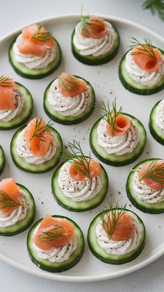 cucumbers with cream cheese and salmon on them are arranged on a white plate
