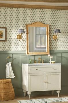 a bathroom with green wallpaper and a white vanity topped with a mirror next to a wicker basket