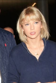 a woman with blonde hair wearing a blue sweater