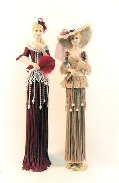 two figurines are standing next to each other wearing dresses and hats with tassels