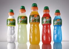 six bottles of fruit punch are lined up in a row on a reflective surface,