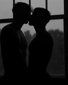 two people are kissing in front of a window