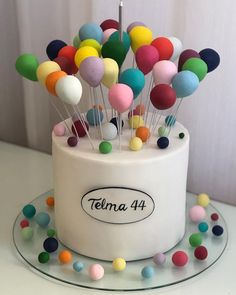 a white cake topped with lots of colorful balloons