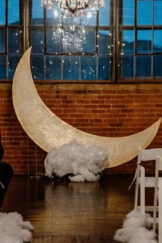 the moon is made out of foam and sits in front of a brick wall, surrounded by white chairs