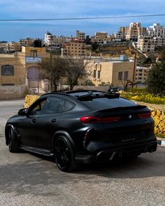 a black sports car parked in front of a city