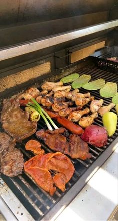 an outdoor grill with meat and vegetables cooking on it