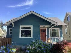 a blue house with flowers in the front yard