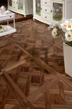 there is a vase with flowers in it on the floor next to a dresser and mirror