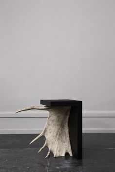 a white and black table sitting on top of a floor next to a gray wall