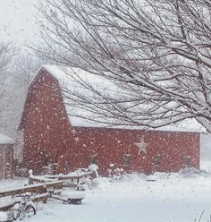 a red barn with snow falling on it