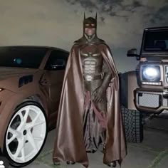 a man in a batman costume standing next to a car