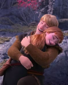 two people hugging each other in front of some rocks