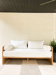 a white couch sitting on top of a tiled floor next to a potted plant