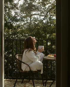 a woman sitting at a table drinking coffee