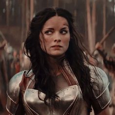 a woman dressed in armor standing next to other people