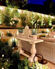 an outdoor dining area with wicker furniture and white flowers on the wall behind it