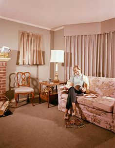 a woman sitting on top of a couch in a living room next to a fire place