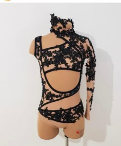 a mannequin with black lace on it's body and back, standing in front of a white wall