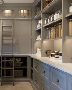 a kitchen with gray cabinets and shelves filled with jars, containers and ladders to the ceiling