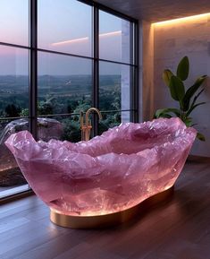 a large pink crystal bowl sitting on top of a wooden floor next to a window