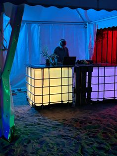 a man sitting at a table with a laptop in front of him on the beach