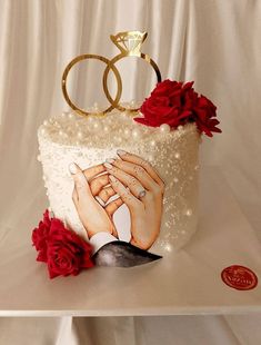 a wedding cake decorated with two hands and roses